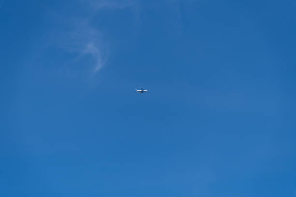 Low angle view of passenger airplane flying in clear blue sky with few cirrus clouds. Copy space for your text. Transportation theme.