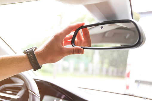 a man's hand corrects the rearview mirror in the car. Mirror with camera and sensors