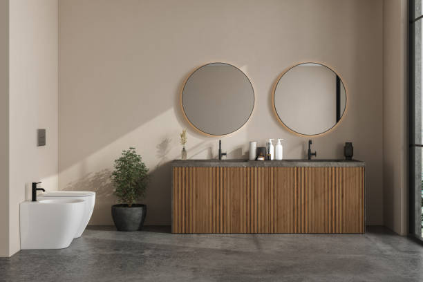 istock Modern bathroom interior with beige walls, marble basin with double mirror and grey concrete floor.Minimalist bathroom with modern furniture. Overlooks tree and landscape view.3D Rendering 1434242547