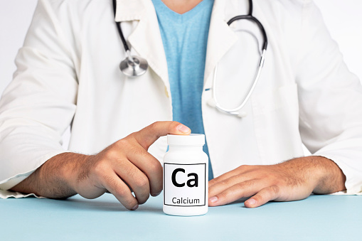 Male doctor and bottle with Calcium Mineral Supplement