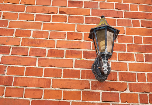 Outdoor lamp on an Old repaired weathered redd brick wall for background, Brick wall. Brick wall texture. brick wall background. bricks wall pattern. Texture brick wall of beige color. Brick pattern, Background of brick. Orange brick. Antique brickwork. Restoration.