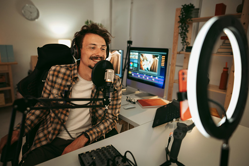 Cheerful man host laughing  while streaming video podcast in broadcasting studio
