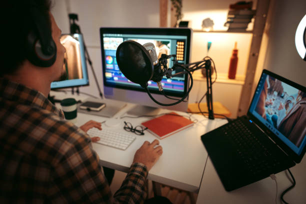 Portrait of confident man sitting on chair in sound recording studio. Record producer is with headphones at workplace. He is wearing casuals.