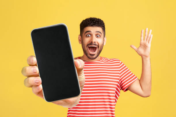 istock Amazed cheerful man showing mobile phone with blank display, expressing happiness, screaming happily 1434251612