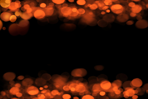 Orange blury horizontal background with light bokehs on black and free space at mid
