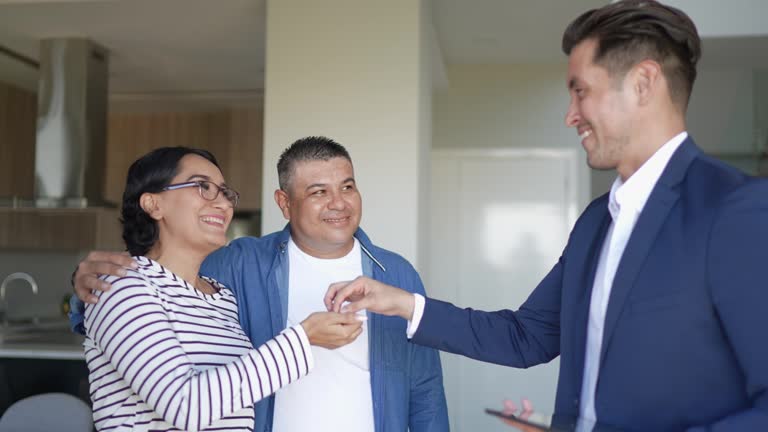 Real estate agent giving house keys to a couple at home