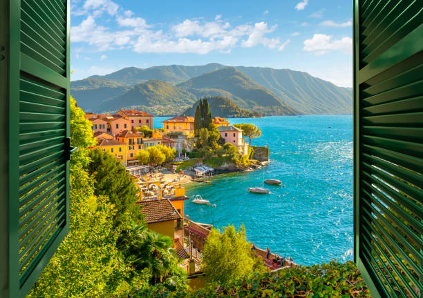 vue à travers une fenêtre ouverte avec des volets donnant sur le village pittoresque coloré de varenna, en italie, sur les rives du lac de côme en été. - come in were open photos et images de collection