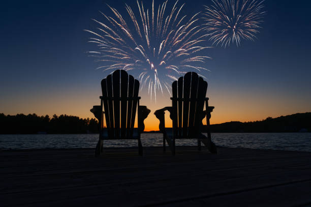 zwei leere adirondack-stühle beim feuerwerk auf dem see - canada day fotos stock-fotos und bilder