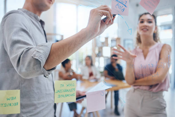 istock Teamwork, sticky notes and business on a board or moodboard in a modern company office. Corporate team, people or staff working together on a pinboard in communication and planning a strategy. 1434285832