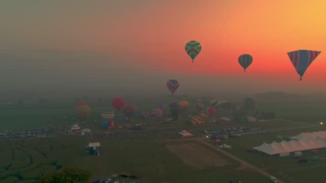 Drone View of Multiple Hot Air Balloons Getting Ready to Launch on a Foggy Morning