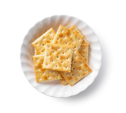Crackers in a dish placed on a white background. View from directly above.