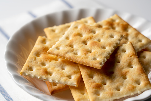 Lots of crackers in a plate placed on a white background with space. Close-up.
