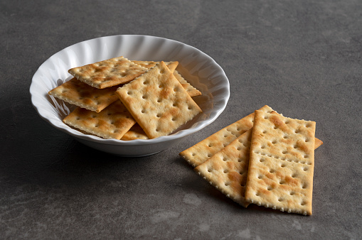 Crackers in a dish set against a dark stone background. Close-up.