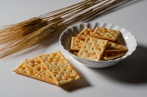 Crackers and ears of wheat in a dish placed on a white background. Close-up.