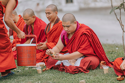 Thimphu, Bhutan - October 7: Bhutanese Monks Lunch Break Sitting On Ground Beside Dochula Passon October 7, 2022 in Thimphu, Bhutan.
