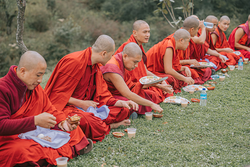 Thimphu, Bhutan - October 7: Bhutanese Monks Lunch Break Sitting On Ground Beside Dochula Passon October 7, 2022 in Thimphu, Bhutan.