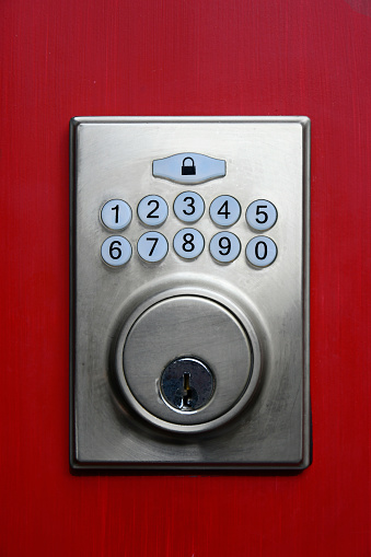 A close up image of a digital key pad on a red painted exterior door.