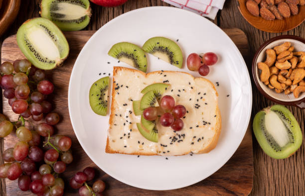 istock Spread the bread with jam and place it with kiwi and grapes on a white plate. 1434299367