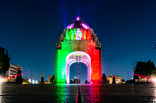 The Monument to the Mexican Revolution illuminated in green, white and red at night.