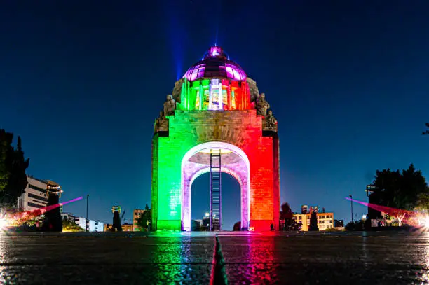 The Monument to the Mexican Revolution illuminated in green, white and red at night.