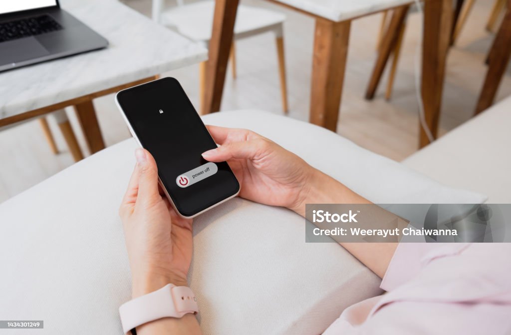 Woman hand using is sliding to turn off the mobile phone to reduce power consumption. Technology and environment concept Turning On Or Off Stock Photo