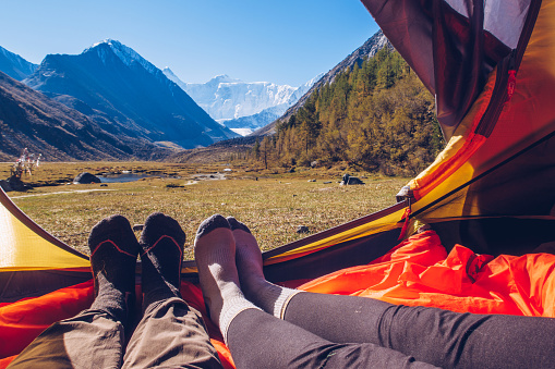Two people lying in tent with a view of mountains. Belukha Mountain view from the tent in Akkem lake valley. Altai picturesque valley view.