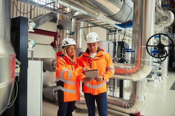 Engineers standing together in a power station and checking a tablet stock photo