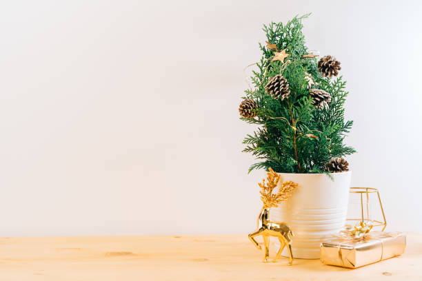 istock Creative natural miniature Christmas tree in pot on wooden table with gift boxes and white background. Xmas greeting card with copy space. Happy New Year. 1434308991