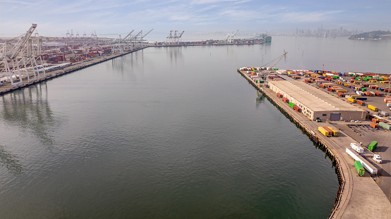 Aerial stock photos of large scale commercial shipping cargo container ships moored in Oakland alongside Alameda California.