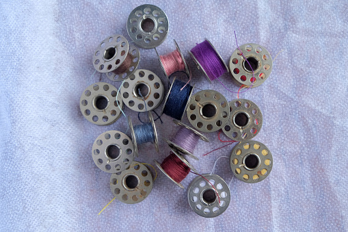 Multicolored threads on the bobbin from the sewing machine on a white background, high angle view