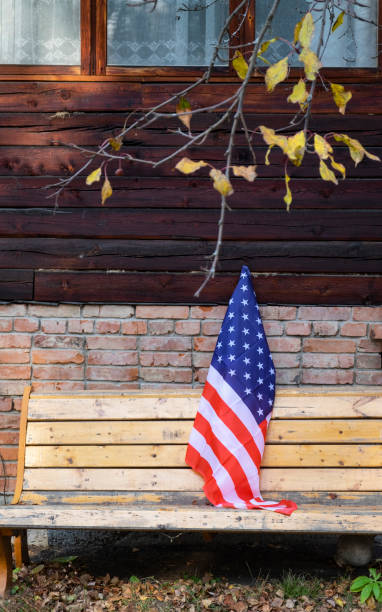 la bandiera americana si trova sul lato sinistro della casa di mattoni. america, foglie autunnali sull'albero. foto verticale - chair brick organized group community foto e immagini stock