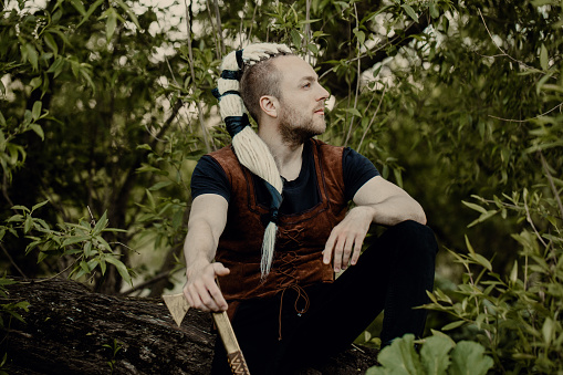 A young man with an interesting depicts a Viking with an ax in an unreliable stylized modern costume.