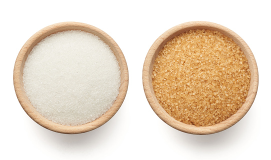 White and brown sugar in wooden bowls on a white background