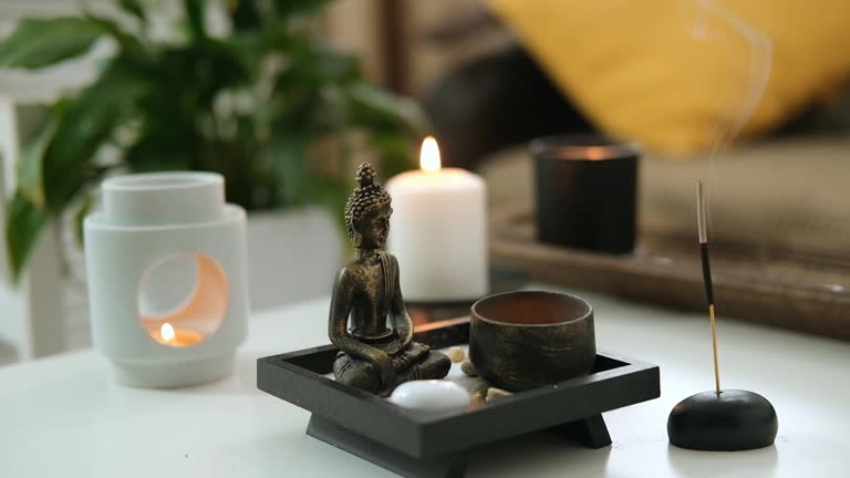 Vintage bronze statuette with candlestick made of copper. Statue of Buddha, incense sticks and burning candle. Aromatherapy, home fragrance. Concept of home relaxation and anti stress, zen buddhism.