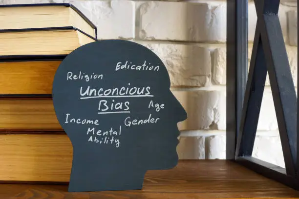 Photo of A stack of books and a head with an inscription unconscious bias.