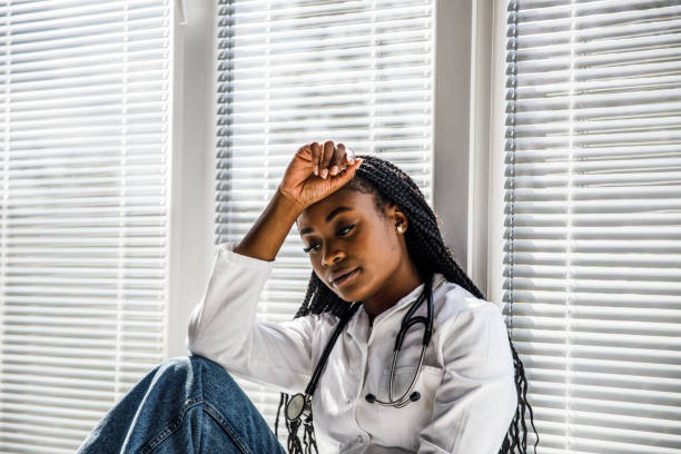 istock Doctor sitting against the window, hand on head, contemplating 1434337970