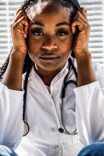 istock Female doctor holding head in hands, looking at camera during work break 1434337974