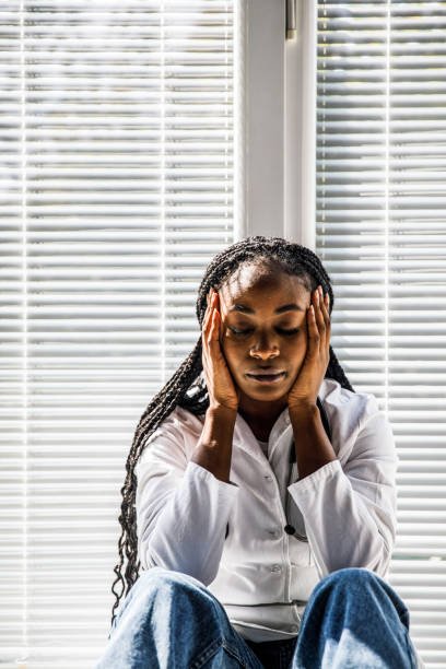 istock Tired doctor sitting with head in hand, eyes closed, taking a break from a hard day at work 1434337975