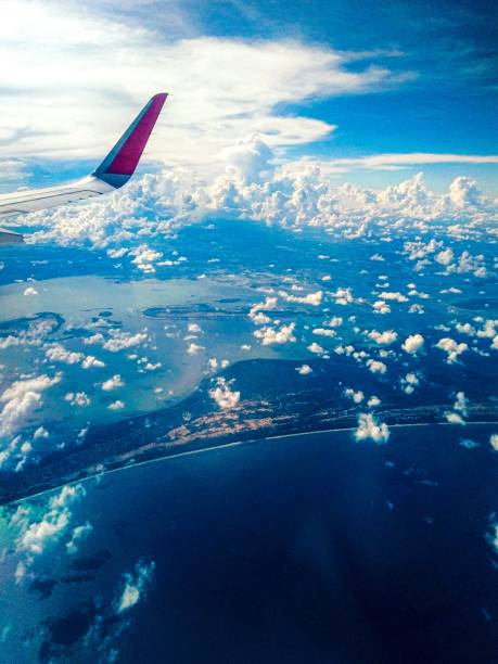 Aircraft wing above blue ocean view.