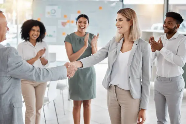 Photo of Handshake, partnership and congratulations after hiring new employee or leadership promotion with applause. Welcome, thank you or b2b agreement of corporate staff shaking hands for support and trust