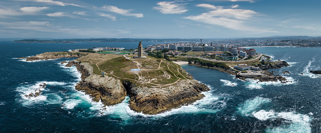 A Coruña famous ancient roman Hercules Tower - Tower of Hercules Coastal Lighthouse and City and Harbor Aerial View from the Atlantic Ocean. Aerial Drone Point of View Stiched Panorama looking towards the famous Hercules Tower. A Coruna, Galicia, Northern Spain, Spain, Europe.