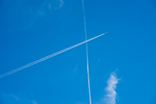 Airliner at high altitude with white condesation trails, on deep blue sky