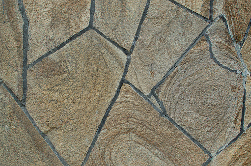 Texture of mosaic masonry of natural stone with grouting on cement mortar.
