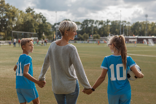 Female soccer football coach with son and daughter during a training session at the football pitch