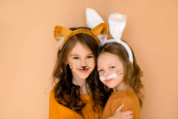 Children with painted faces in rabbit and tiger costumes are hugging and smiling sweetly. The old new year meets the new one. Stage animal costumes. Children with painted faces in rabbit and tiger costumes are hugging and smiling sweetly. The old new year meets the new one. Stage animal costumes. cat face paint stock pictures, royalty-free photos & images
