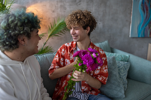 A young homosexual man surprised after receiving flowers from his boyfriend