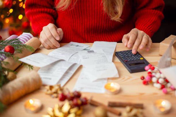 femme assise à table, vérifiant ses factures après avoir tout acheté pour noël - dépense photos et images de collection