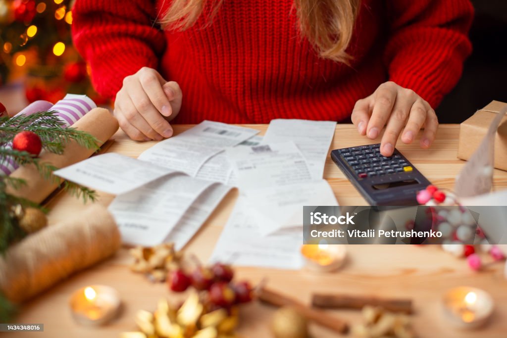 Woman sitting at the table, checking her bills after buying everything for Christmas Winter holidays shopping, expensive time of the year Vacations Stock Photo