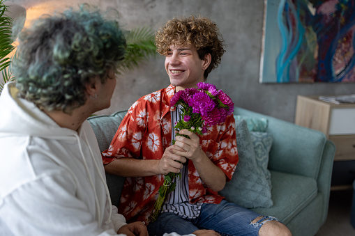 A young homosexual man surprised after receiving flowers from his boyfriend