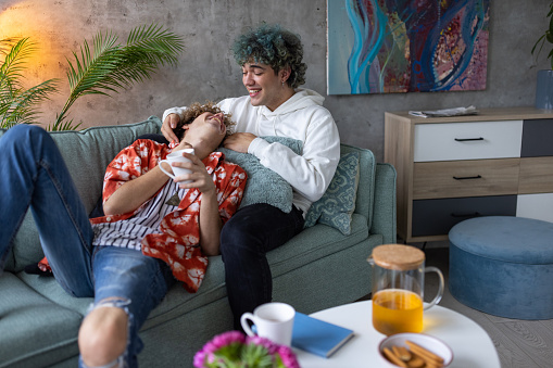 Two young adult gay men embracing in their apartment living room
